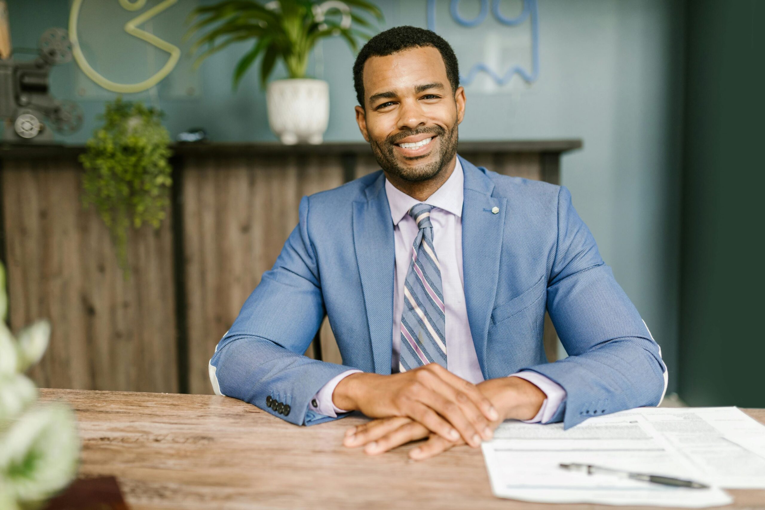 A male accountant is looking ahead while sitting and smiling.