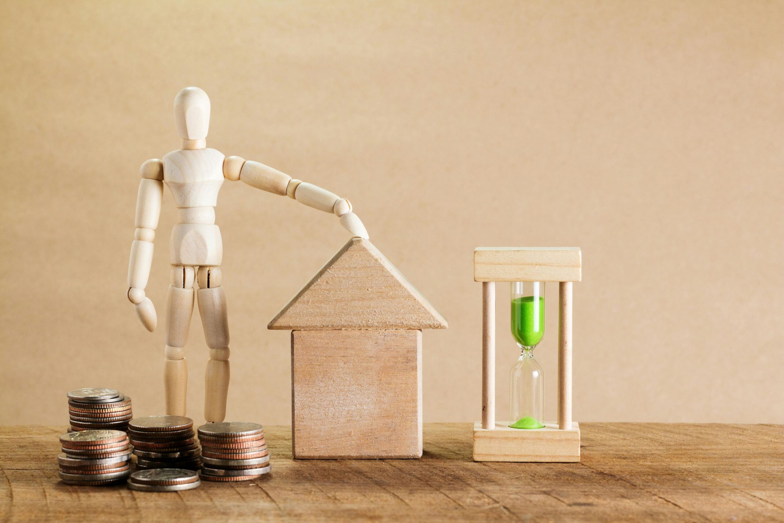 An image of a wooden person, wooden house and hour glass side by side.