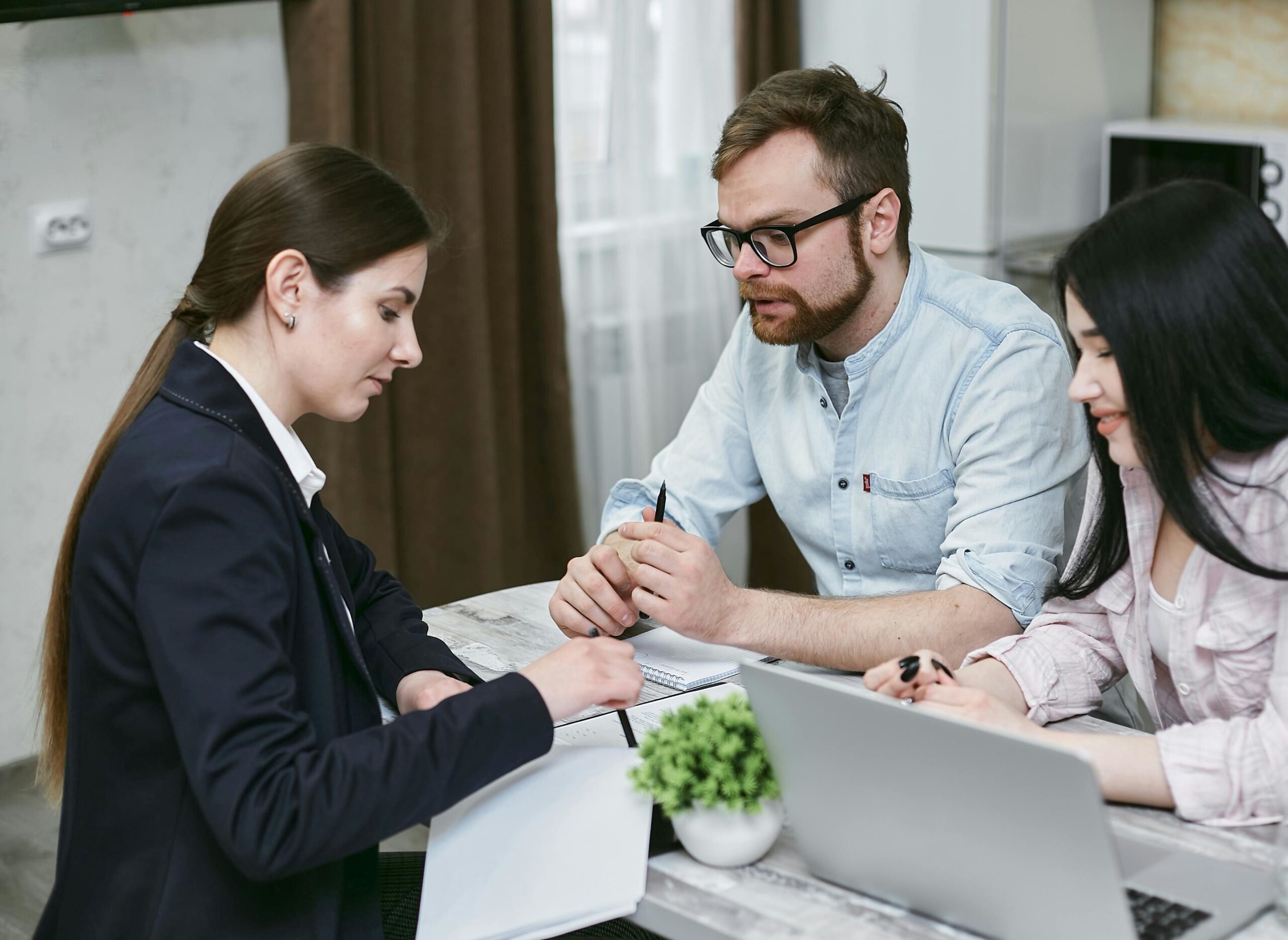 A couple is engaged in a discussion with a female broker.