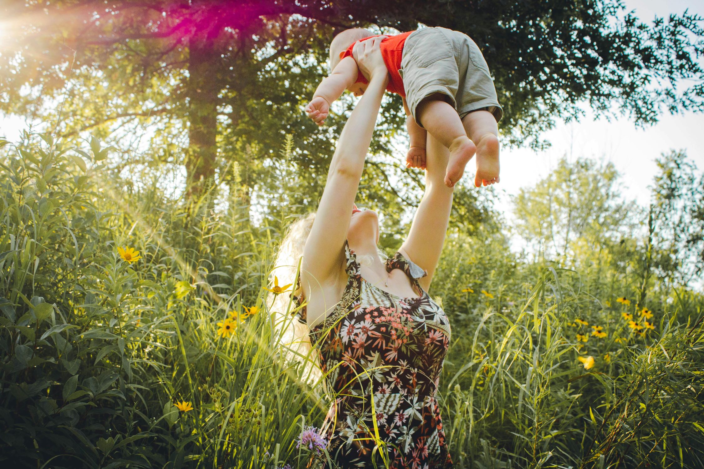 A mother is lifting up her baby.