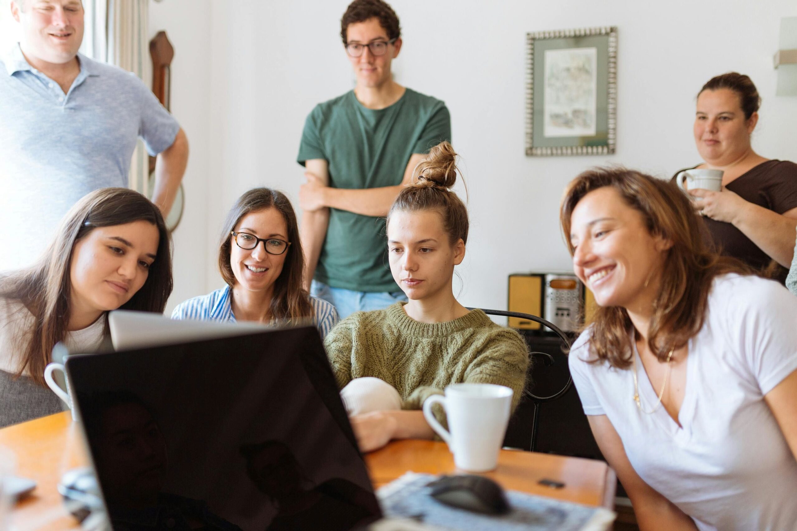 A family of siblings gathered around a laptop.