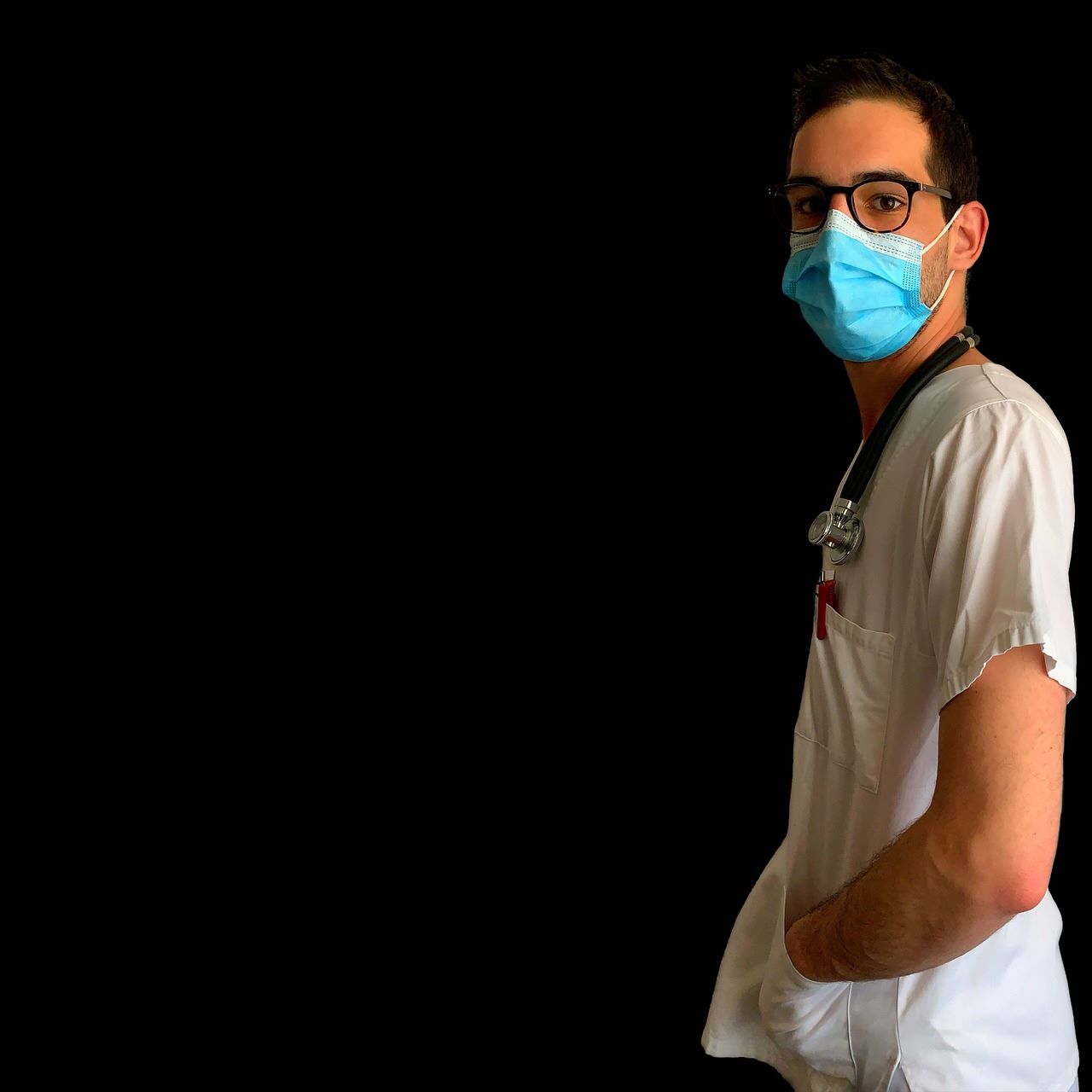 A male nurse in a surgical mask and glasses, dedicated to patient care in a healthcare environment.