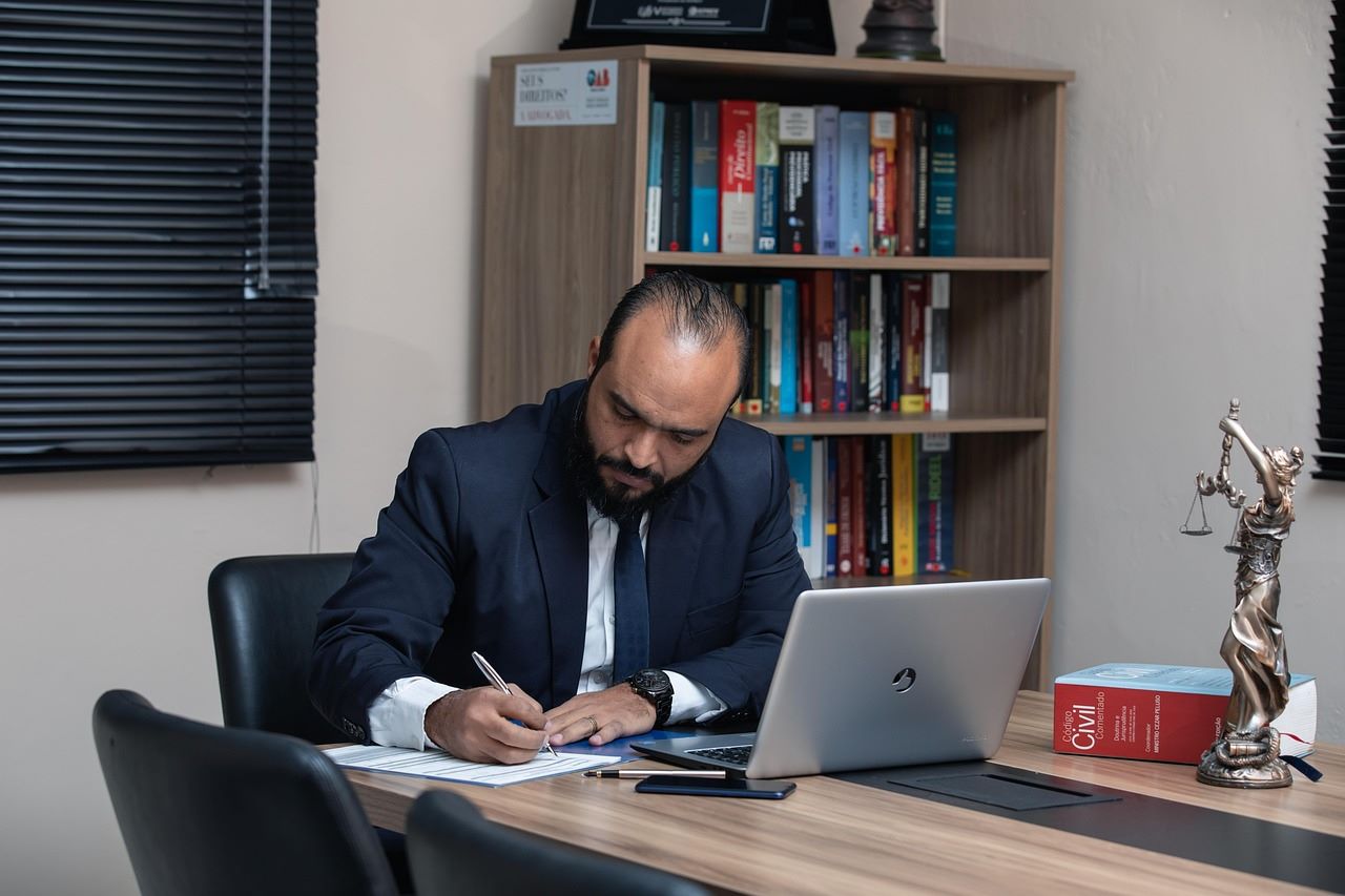 A male lawyer in a suit seated at a desk, focused on his laptop, exuding professionalism and concentration.