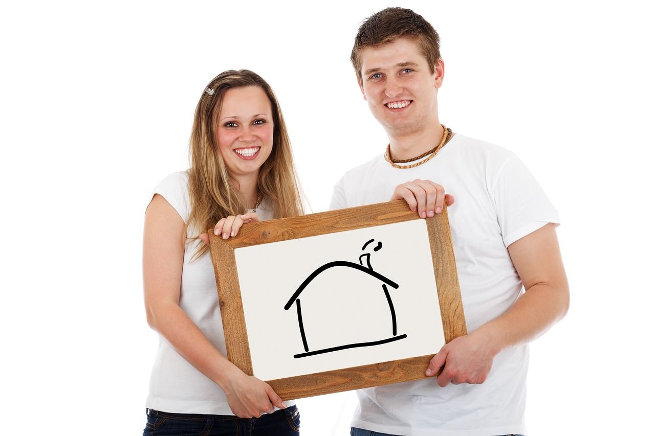 A man and woman proudly display a sign featuring a house, symbolizing their mortgage pre-approval journey.